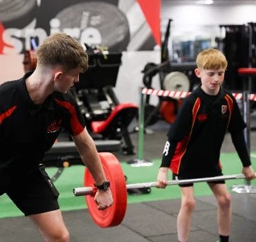 Coach teaching young athlete proper weightlifting technique at The Athlete Academy